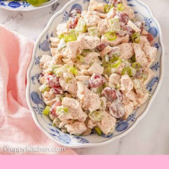 Pinterest graphic of an overhead view of a platter of chicken salad with a pink linen and a serving plate off to the side.