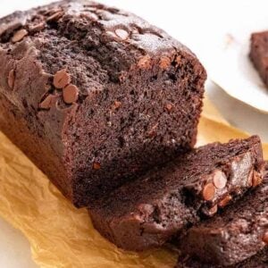 A loaf of chocolate zucchini bread with slices cut in front of it.