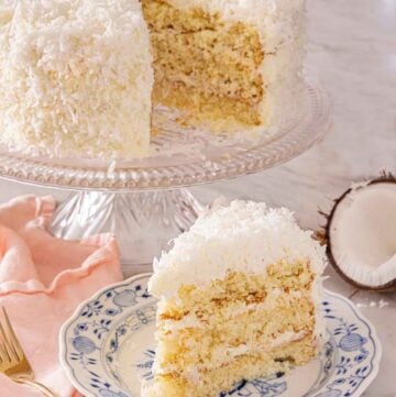 A plate with a slice of coconut cake in front of a cake stand with the rest of the cake.