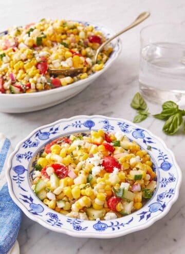 A plate of corn salad with a serving platter in the background.