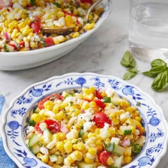 Pinterest graphic of a plate of corn salad with a platter in the background along with some basil and a glass of water.