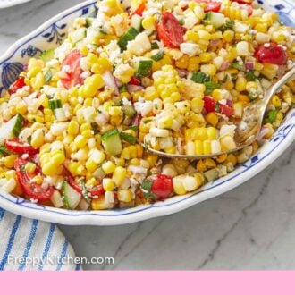 Pinterest graphic of an oval platter of corn salad with a serving spoon scooped in.