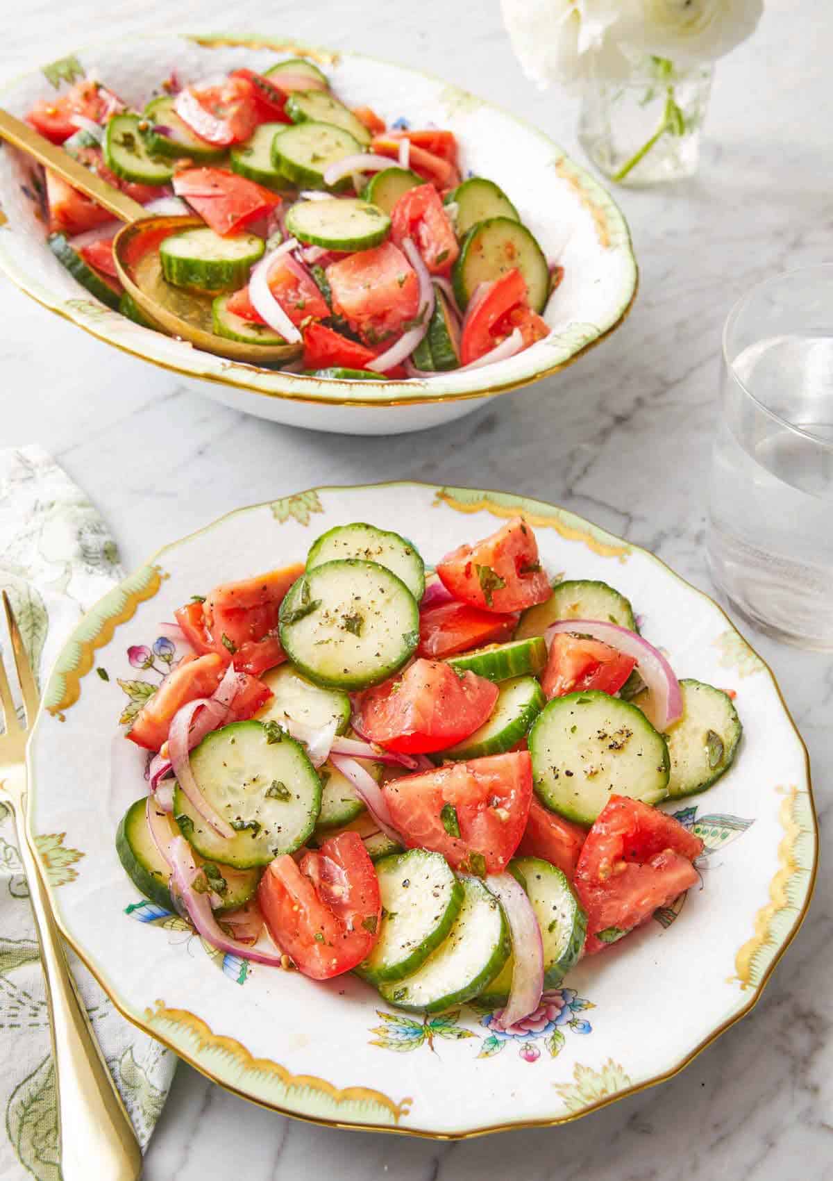 A plate of cucumber tomato salad with a platter full in the background.