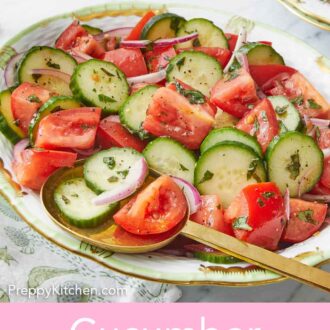 Pinterest graphic of an oval platter of cucumber tomato salad with a spoon tucked under a few pieces.