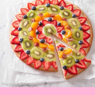 Pinterest graphic of a fruit pizza on a sheet of parchment paper with a slice cut and pulled out.