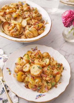 A plate of German potato salad with a serving platter in the background.