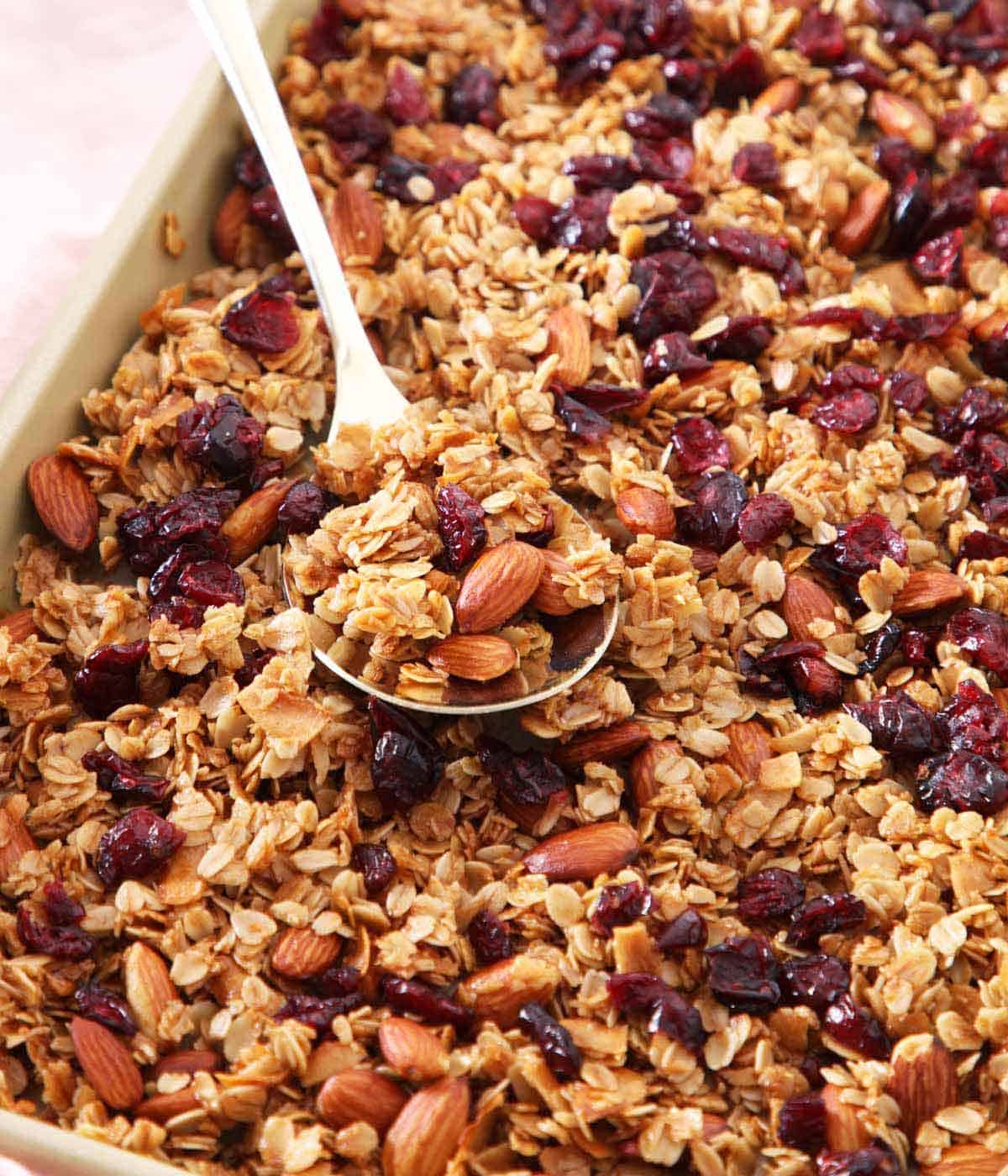 A sheet pan with granola with a spoonful on top.
