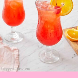Pinterest graphic of two glasses of hurricane drink with an orange slice on each glass rim and a cherry garnish.