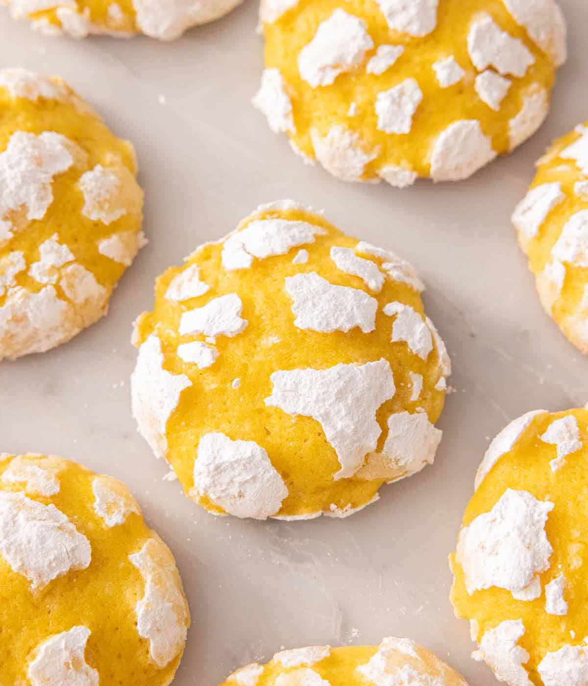 Multiple lemon crinkle cookies on a marble surface.