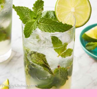 Pinterest graphic of a slightly overhead view of a glass of mojito with fresh mint and lime garnishing the drink.