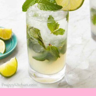 Pinterest graphic of a glass of mojito with fresh mint and sliced lime on the top of the glass. Lime wedges on the counter.