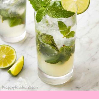 Pinterest graphic of a glass of mojito with sliced lime on the counter beside it.