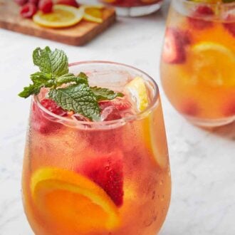 Pinterest graphic of a glass of rose sangria with another in the background along with a pitcher.