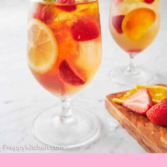 Pinterest graphic of two glasses of rose sangria with fresh mint on top. Cut fruit on the side.