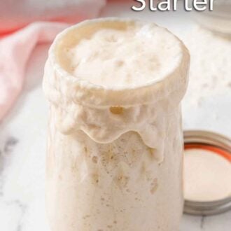 Pinterest graphic of a tall jar of bubbly sourdough starter with some overflowing.