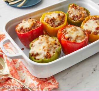 Pinterest graphic of a white baking dish with six stuffed peppers with forks on a plate in the background.