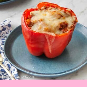 Pinterest graphic of a stuffed pepper with melted cheese on top on a blue plate.