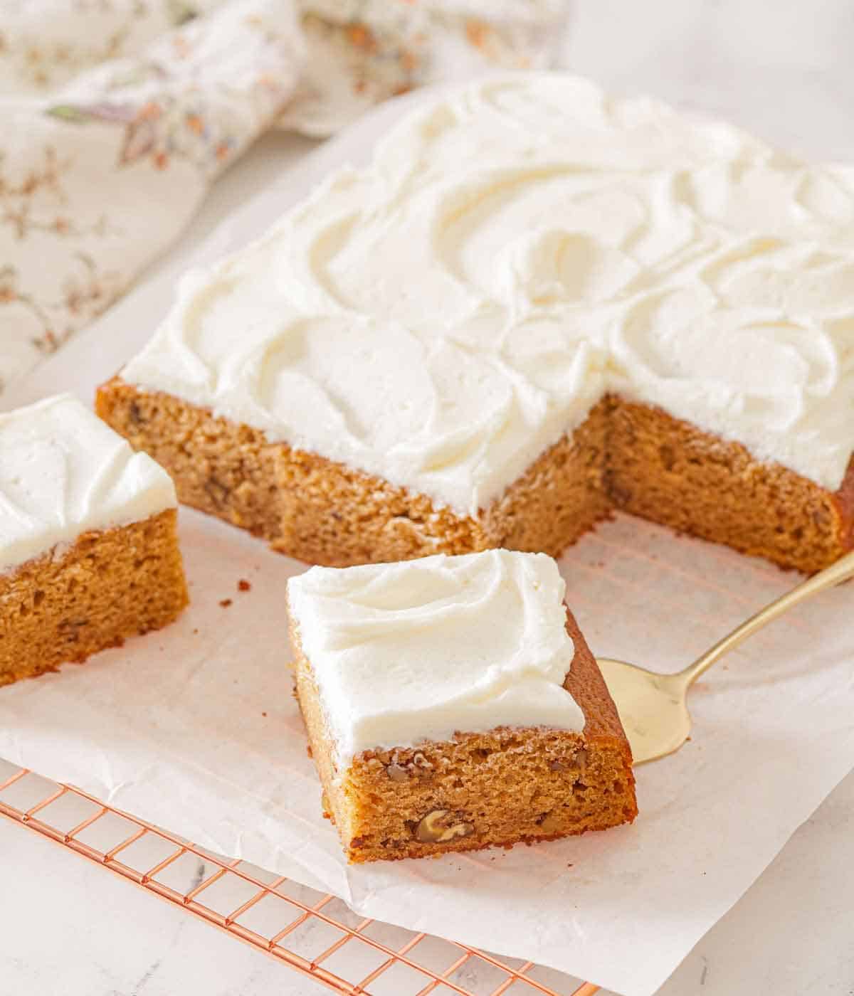 An applesauce cake with a few slices cut with one slice pulled forward with a cake spatula.