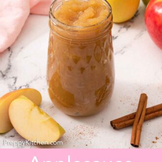 Pinterest graphic of a tall mason jar of applesauce with sliced and whole apples scattered with cinnamon sticks.
