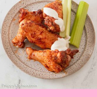 Pinterest graphic of a plate with chicken wings and celery with sauce drizzled over.
