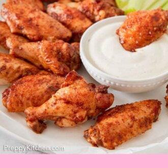 Pinterest graphic of a platter of chicken wings with one dipped into a small bowl of sauce.