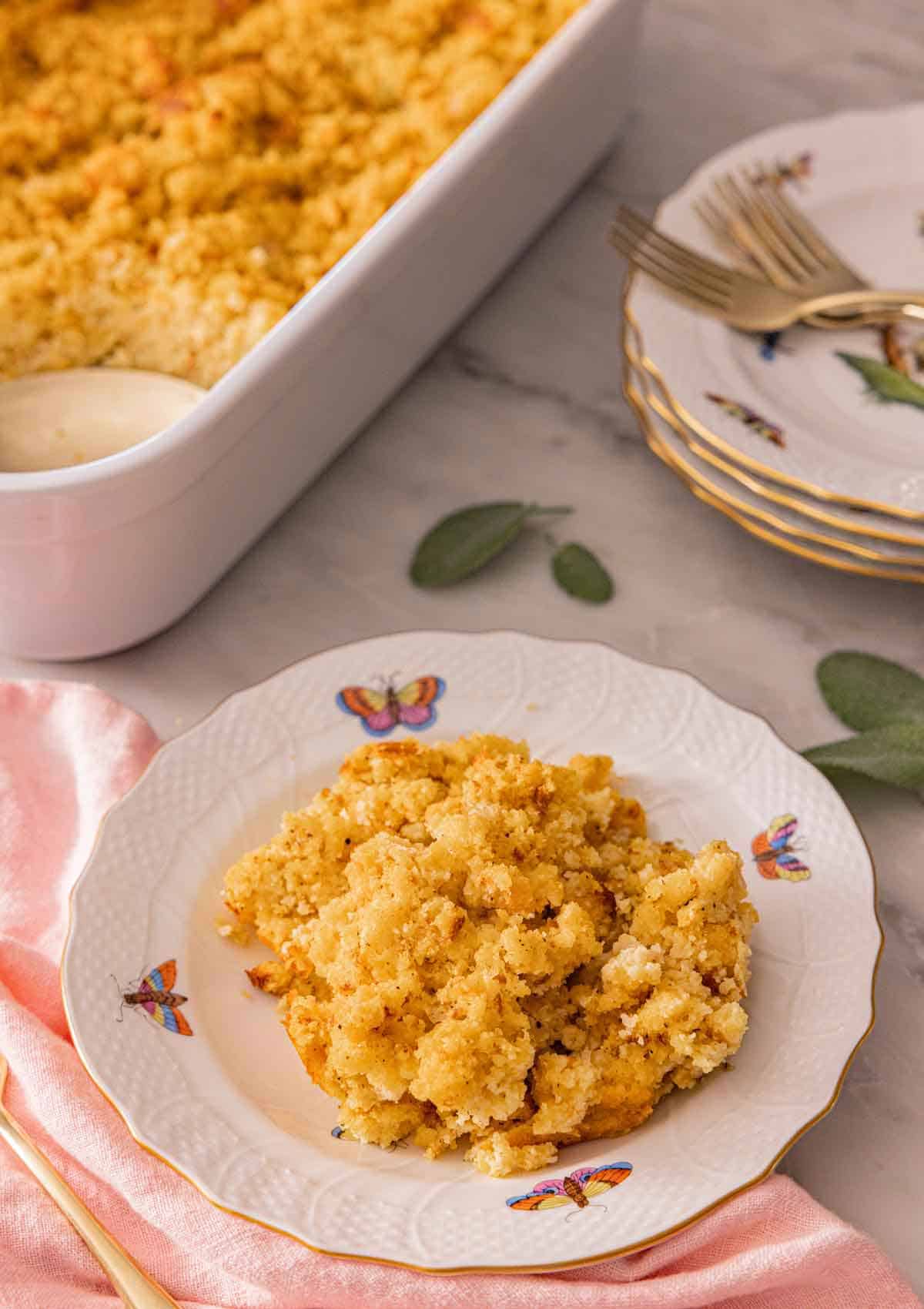 A plate of cornbread dressing with a baking dish in the background.