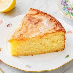 A plate with a slice of olive oil cake with a fork beside it on a linen napkin.