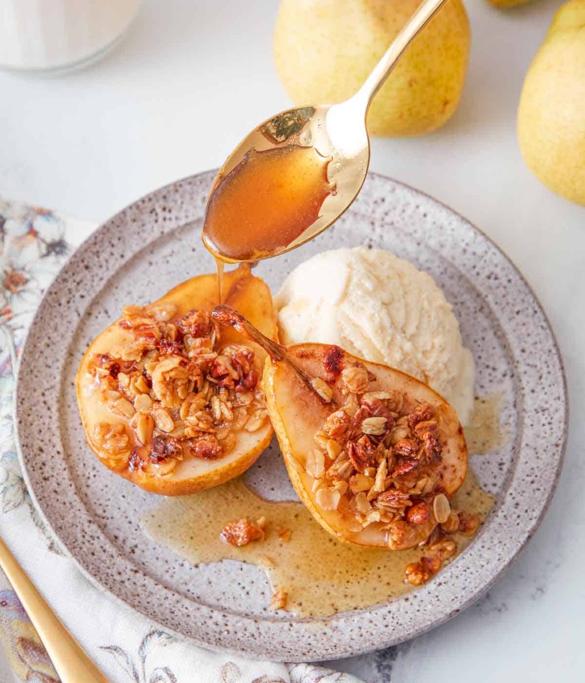 A plate with two baked pears with a scoop of ice cream with caramel drizzled on top.