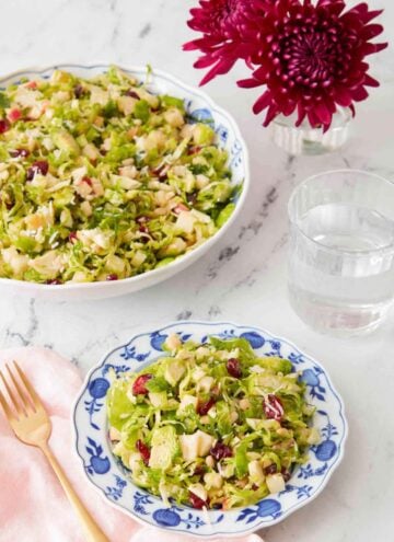 A plate of Brussels sprout salad with a large serving bowl with more in the background.