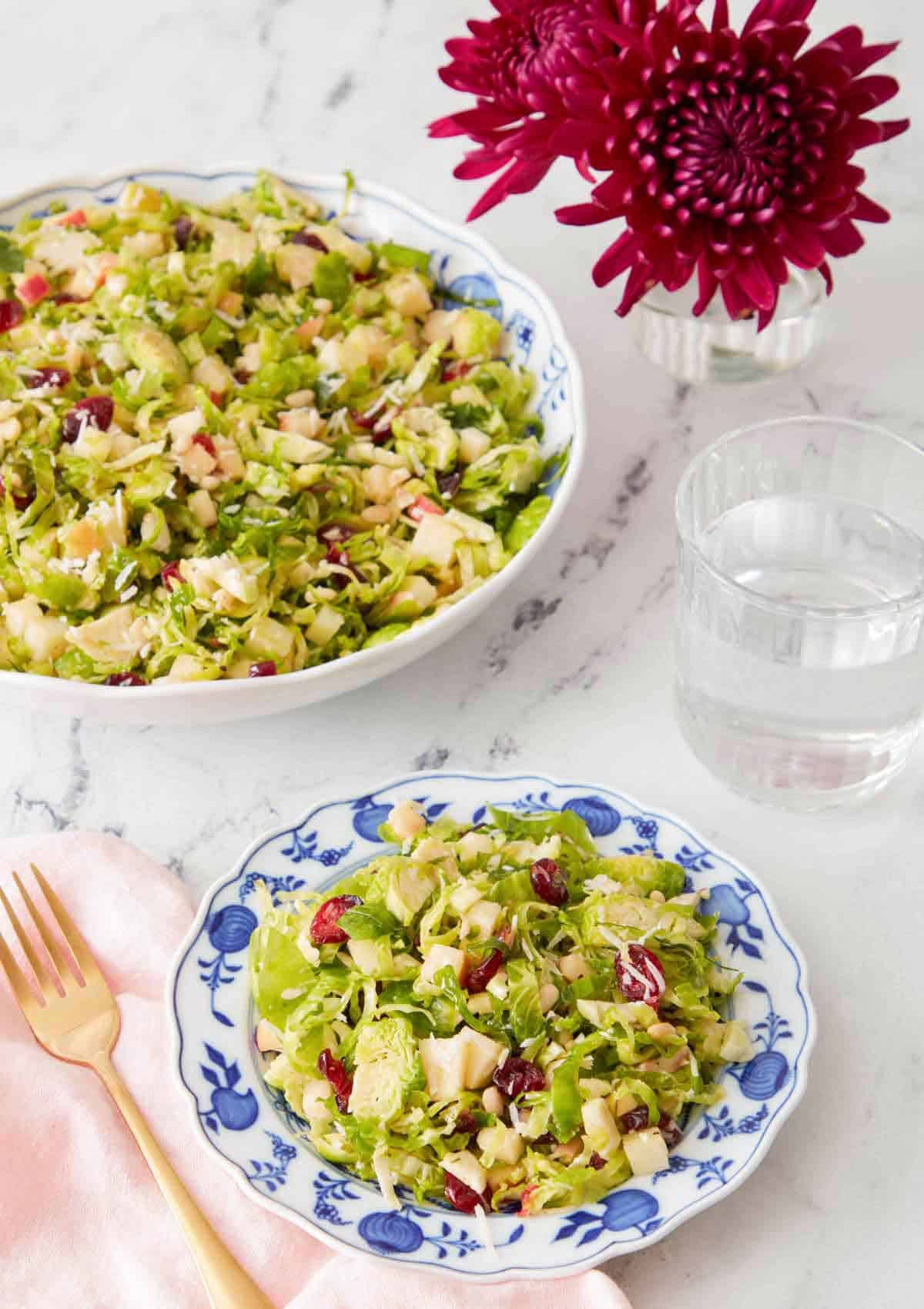 A plate of Brussels sprout salad with a large serving bowl with more in the background.