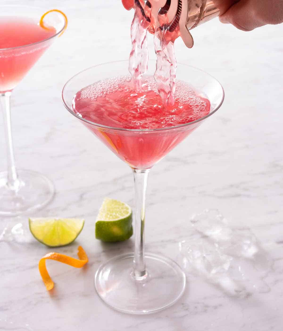 Cosmopolitan strained out of a cocktail shaker into a martini glass.