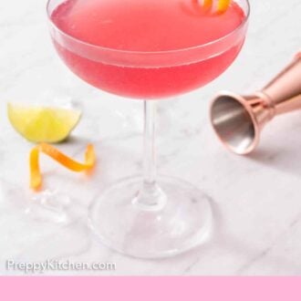 Pinterest graphic of a glass of Cosmopolitan with an orange peel garnish inside. A jigger and citrus in the background.