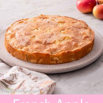 Pinterest graphic of a plate with a round French apple cake with fresh apples in the background.