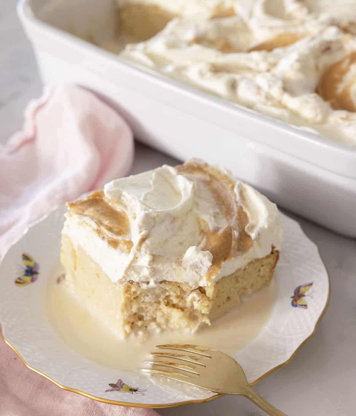 A piece of peanut butter tres leches cake on a a plate with a forkful removed.