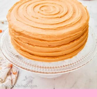 Pinterest graphic of a frosted caramel cake on a clear cake stand with two plates in the background.