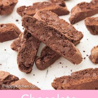 Pinterest graphic of multiple chocolate biscotti on a white surface with a small pile in the middle.