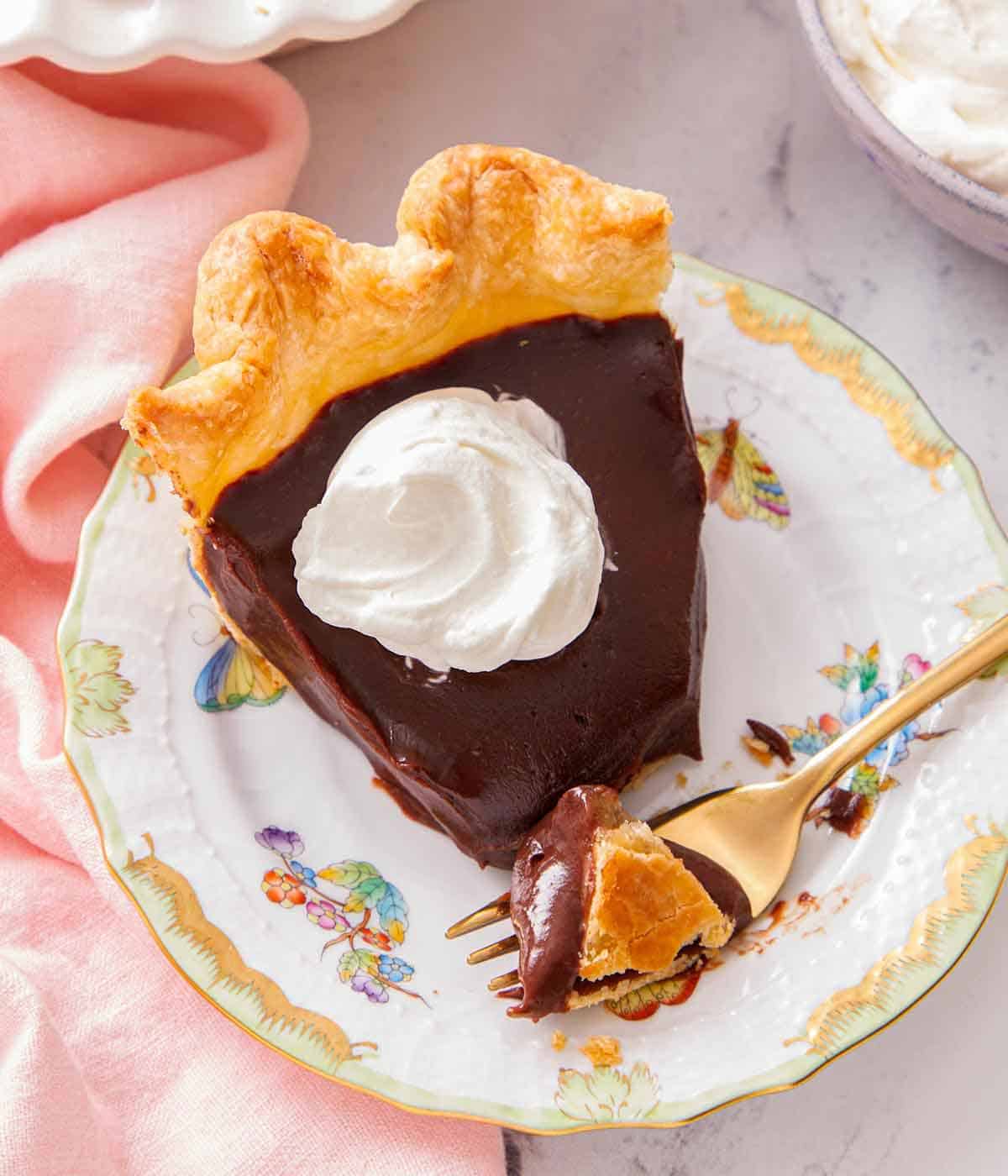 A plate with a slice of chocolate pie with a dollop of whipped cream on top.