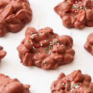 A marble surface with multiple pieces of crockpot candy with a couple with sprinkles on it.