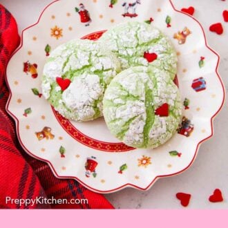 Pinterest graphic of a festive plate with three Grinch cookies with heart sprinkles pressed on.
