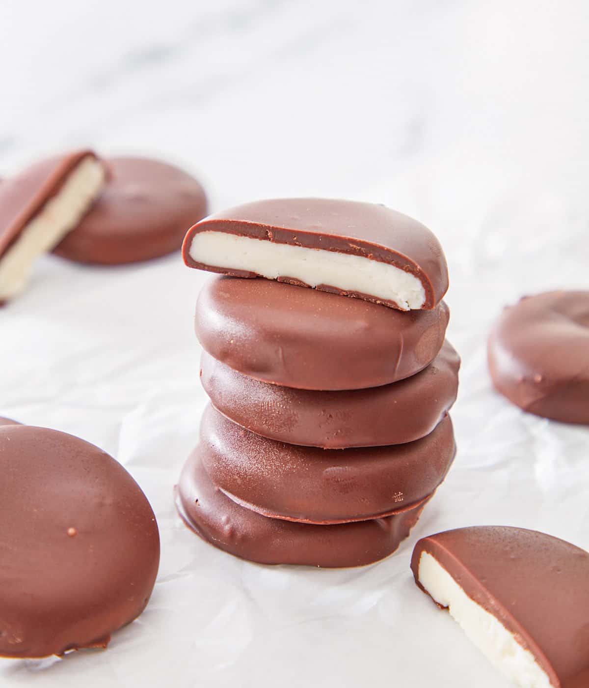 A stack of five peppermint patties with the top one cut in half to show the middle.