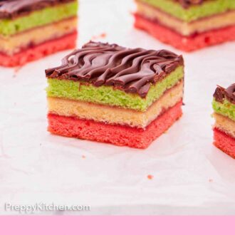 Pinterest graphic of rainbow cookies with one in the middle, in focus, showing the three colored layers with chocolate on top.