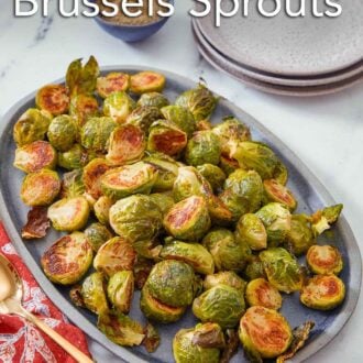 Pinterest graphic of an oval serving platter of roasted Brussels sprouts.