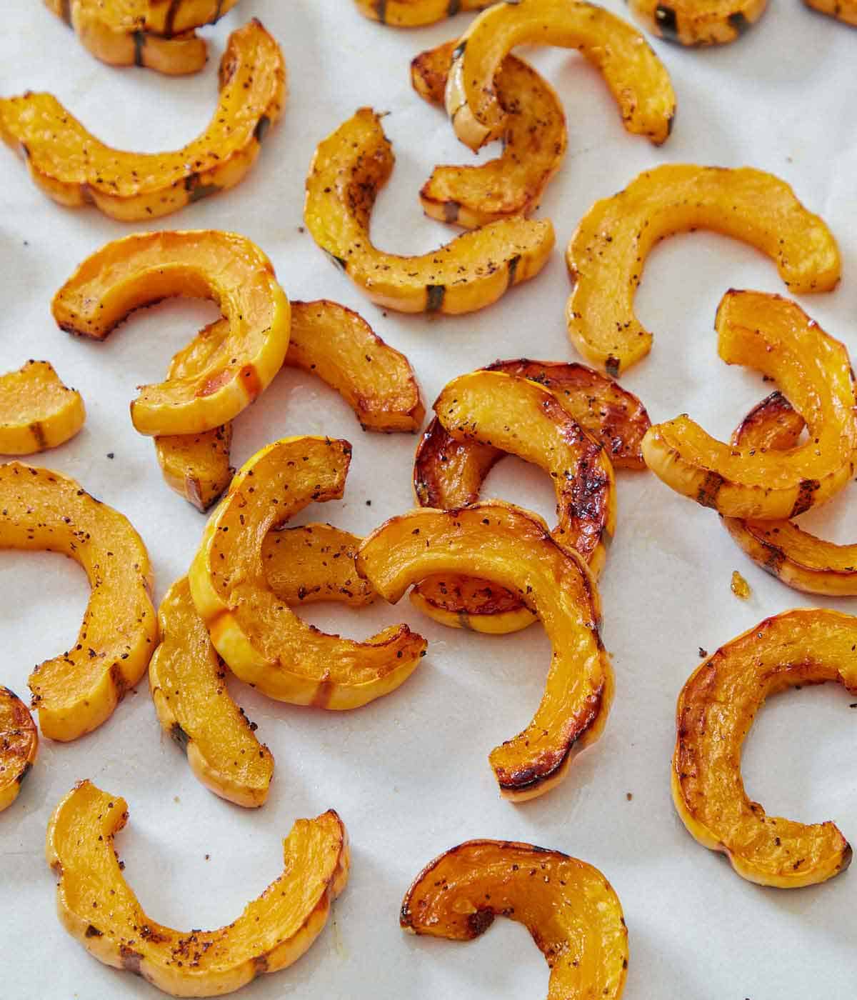 Roasted delicata squash on a white surface.