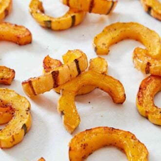 A white counter with multiple pieces of roasted delicata squash.