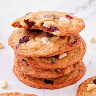 A stack of white chocolate cranberry cookies with a bite taken out of the top cookie.