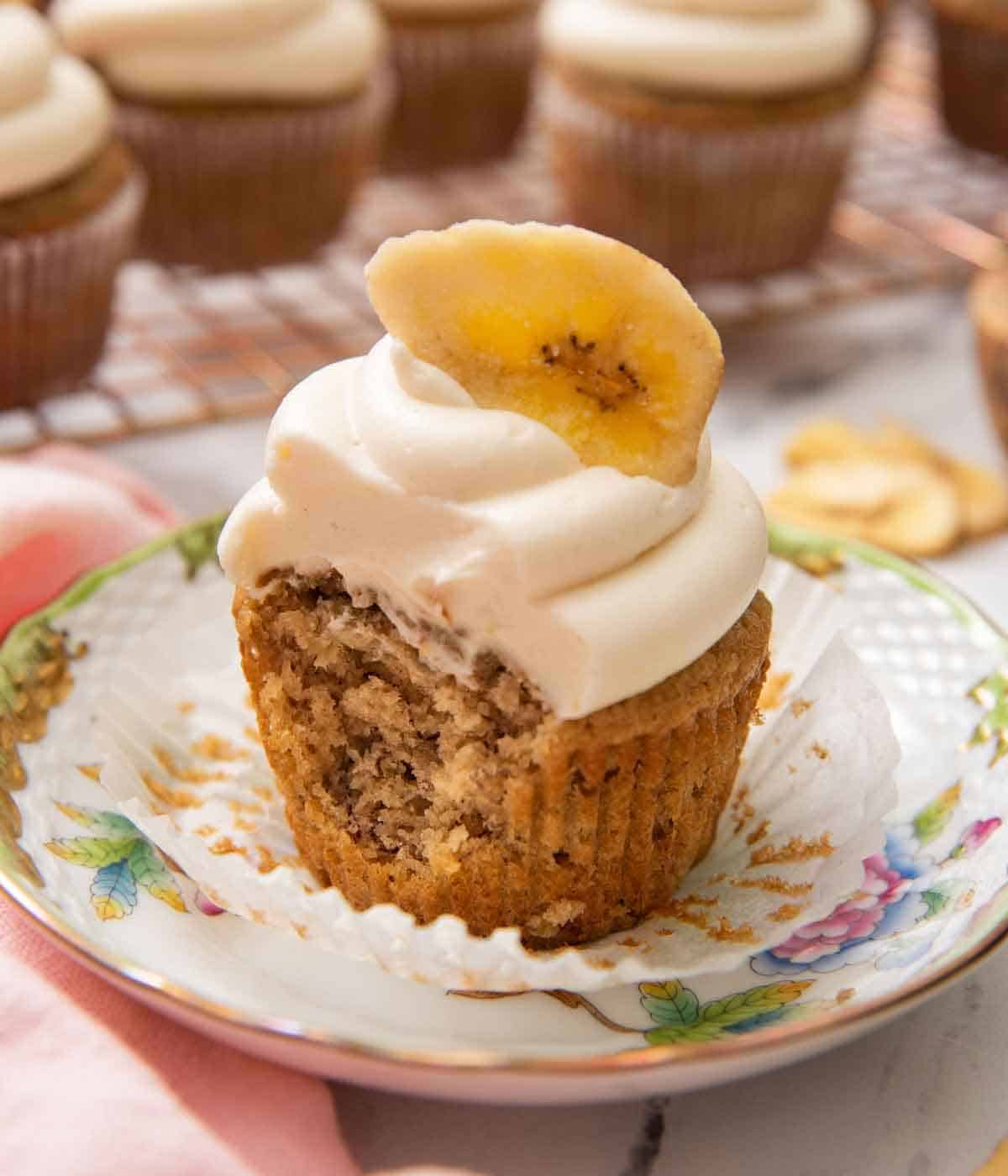 A banana cupcake with the liner pulled out with a bite taken.