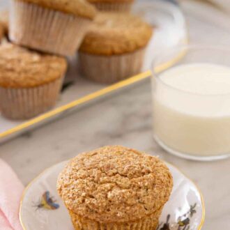 Pinterest graphic of a plate with one bran muffin with a glass of milk and platter of muffins in the back.