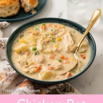 Pinterest graphic of a bowl of chicken pot pie soup with a spoon inside and a glass of water and more biscuits in the back.