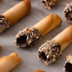 Multiple chocolate dipped tuiles in even rows on a counter.