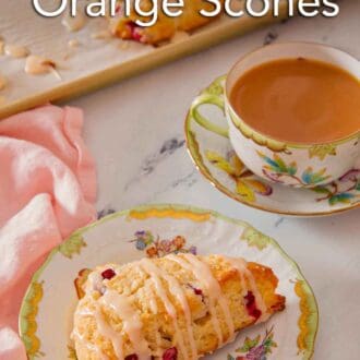 Pinterest graphic of a plate of cranberry orange scone with a drizzle of glaze over top and a mug of coffee in the back.